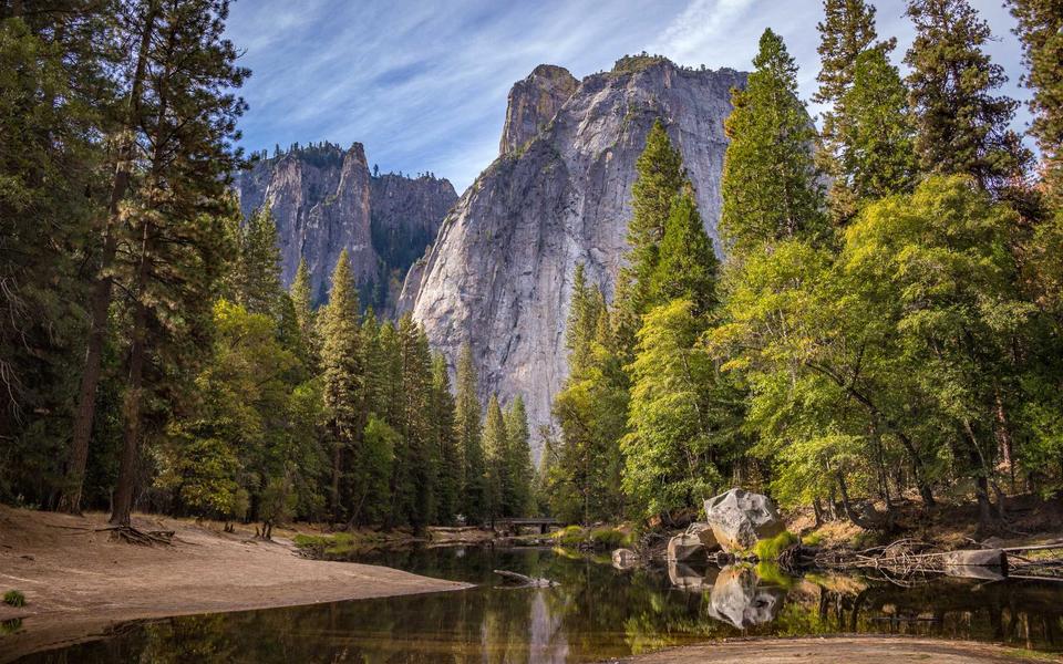 Tall granite cliffs rising above pine trees and a calm river